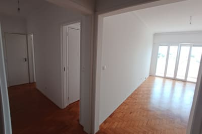 Sala remodelada em apartamento em Carcavelos, vista do corredor para as portas de sacada.