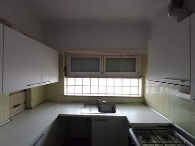 Cozinha com azulejo antigo antes dos trabalhos de remodelação, com janela e armários a substituir.
