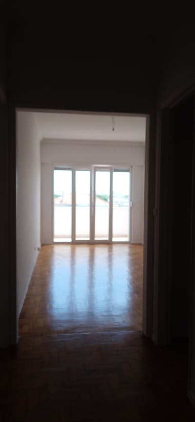 Sala remodelada em apartamento em Carcavelos, com pavimento em madeira recuperado e portas de sacada para varanda.
