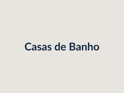 Casa de banho remodelada, com resguardo de vidro, móvel suspenso e revestimento branco.