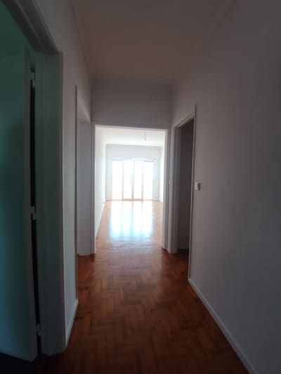 Quarto pintado de branco após remodelação, com luz natural e pavimento em madeira.